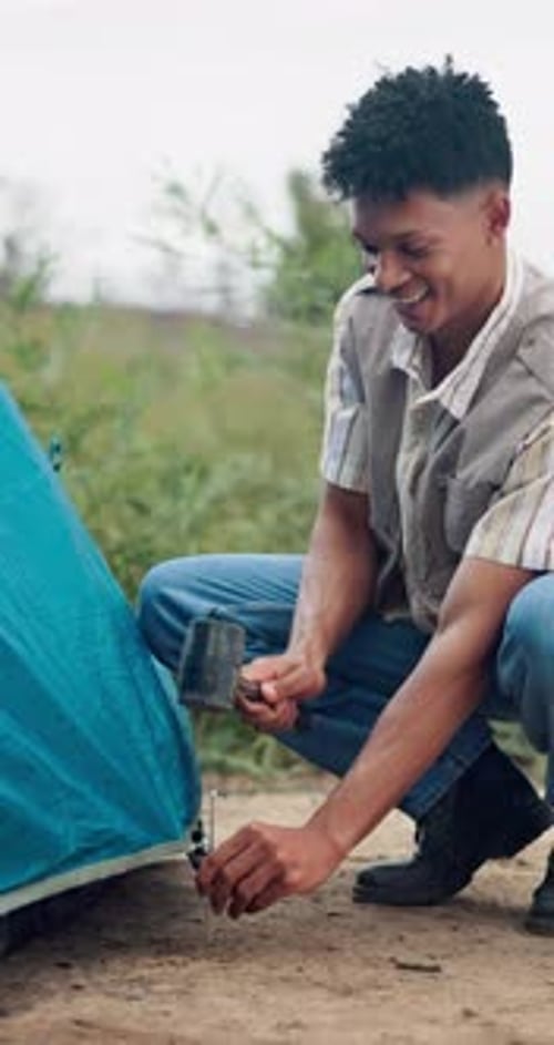 Happy man, tent and setup with peg in nature for camping preparation or secure outdoor shelter