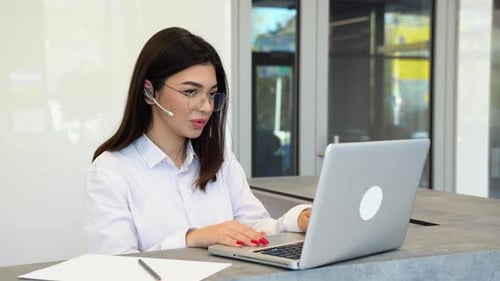 Young Woman Working at Laptop with Headset
