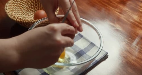 Nahaufnahme eines Küchenchefs, der während des Kochvorgangs in der Küche frische Eier in eine Glasschüssel knackt