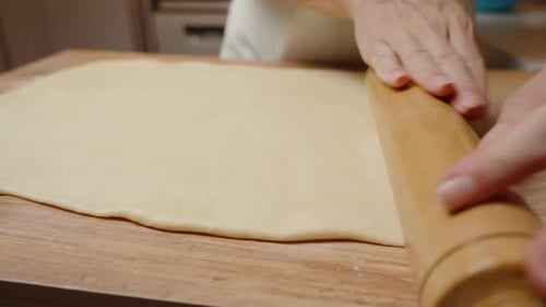 Adult Rolling Dough in a Kitchen