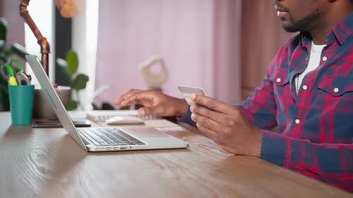 Young Adult Using Laptop and Credit Card at Desk
