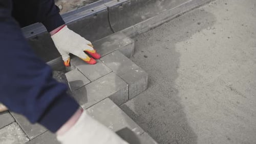 Builder Lays Paving Stones on the Street