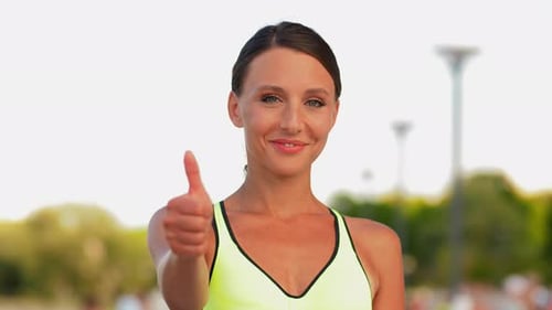 Smiling Woman Gives a Thumbs Up in Sunlight