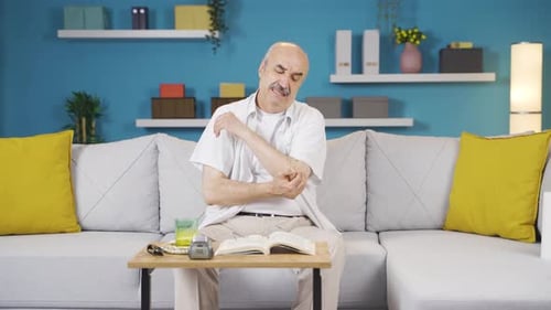 Senior Man Experiences Elbow Pain at Home