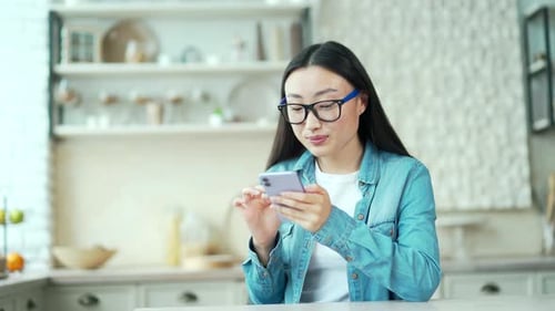 Woman Using Smartphone in Bright Modern Kitchen
