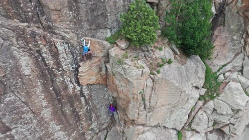 Climber Helping Another Climber Climbing Cliff