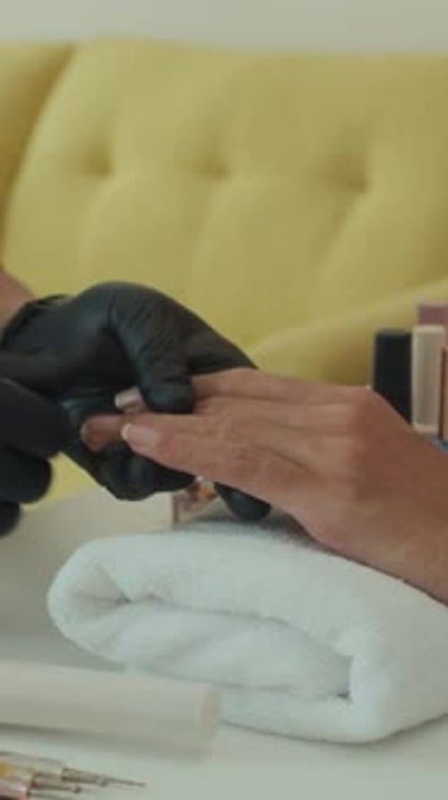 Vertical da manicure, hidratando unhas e dedos da cliente no salão