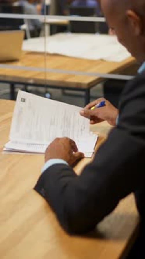 Vertical d'un homme d'affaires africain et de son collègue caucasien signant des documents d'emploi au bureau pendant