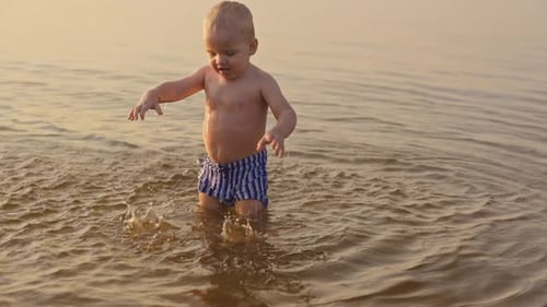Baby Boy Splashing in Shallow Water at Golden Hour