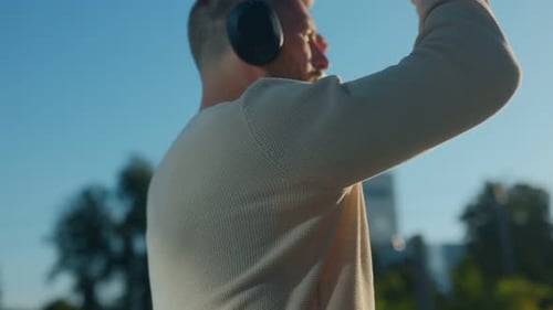 Young Bearded Man Enjoying Music with Headphones in Modern City