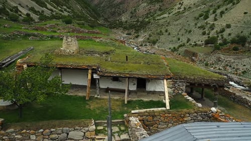 Enchanting Drone View of Historic Stone Building with Roof Covered in Grass in a Scenic Gorge