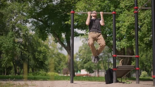 Athletic Man Doing Pull Ups Outdoors in a Park