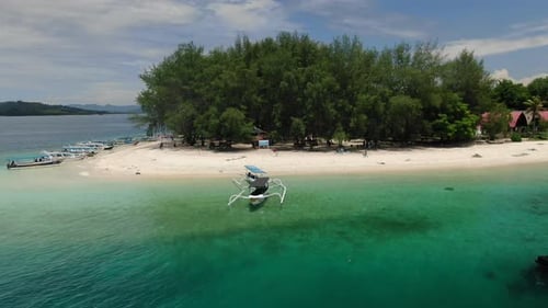 Low angle drone shot around a white sand beach, as boats floating on the water and people walking on