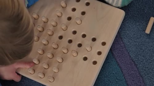 Un enfant joue au jeu de solitaire en bois