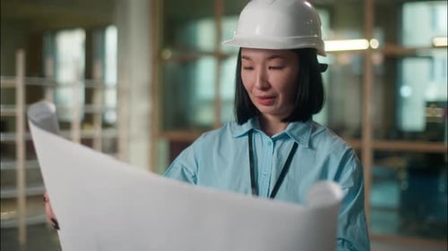 Woman Civil Engineer in Hard Hat Asian Girl Inspector Looking at Building Plan Construction Paper