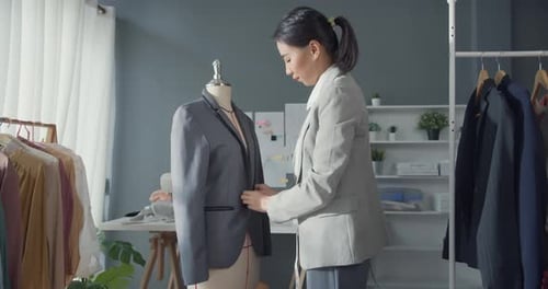 Fashion designer stand work with suit up on mannequin in modern workshop studio.