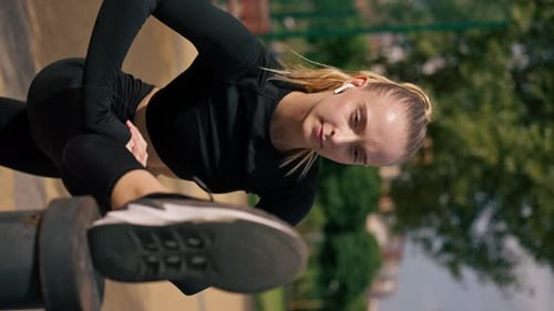 Blonde Young Woman Stretching Leg in Urban Park