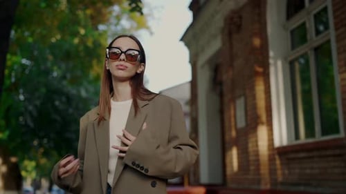 Stylish Woman in Jacket and Trendy Sunglasses Posing on Camera on Street