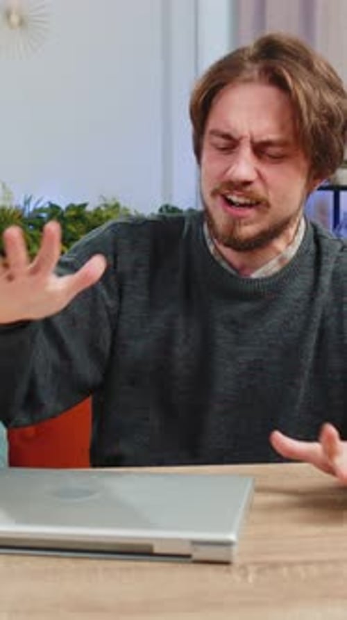 Frustrated man sitting at desk with laptop