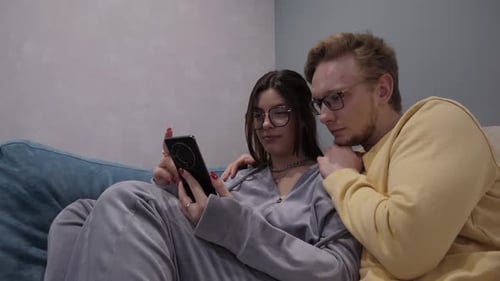 Couple Lying on Couch Looking at Cell Phone
