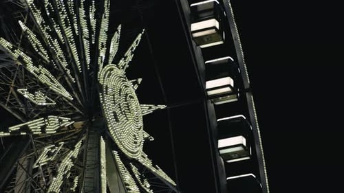 Beleuchtetes modernes Riesenrad mit geschlossenen Kabinen, das sich langsam im Licht der Nachtlichter bewegt
