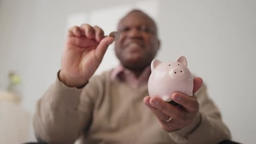 Save Money and Economy Portrait of Black Man Putting Coins Into Piggy Bank Smiling Adult African