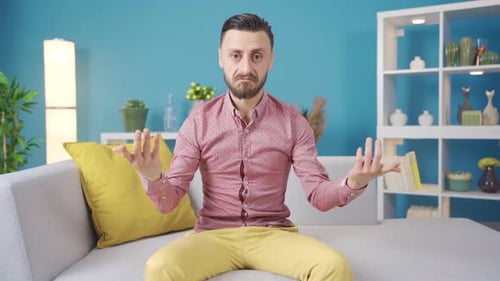 Confused Man Sitting on Couch Indoors