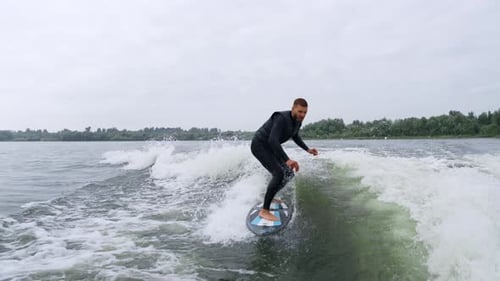 Man Wake Surfing Behind Boat On River