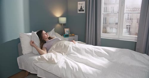 Woman Stretching in Bed on a Sunny Morning