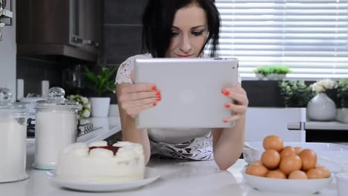 Attractive Brunette Woman in Modern Kitchen Using Tablet Computer While Baking