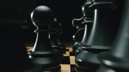 Steadicam-Bewegung entlang der Reihe stehender schwarzer Bauern und Schachfiguren auf dem Schachbrett Chessfield