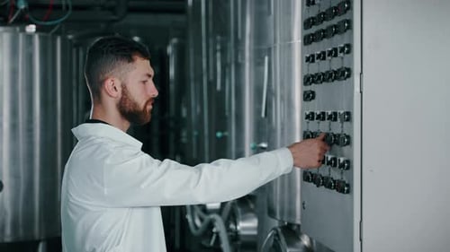 Technologist is Adjusting Control Panel for Modern Equipment in Food Production Plant