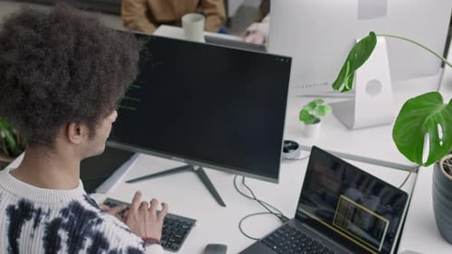 Biracial Male Programmer Coding on Desktop Computer in Office