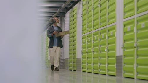 Employé d'entreposage en libre-service marchant avec une boîte en carton le long du couloir