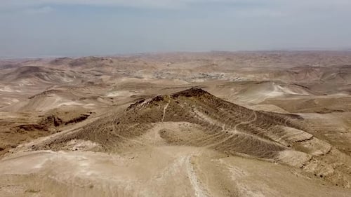 Aerial forward slow and calm drone shot of a mountain in the middle of an empty desert and blue sky