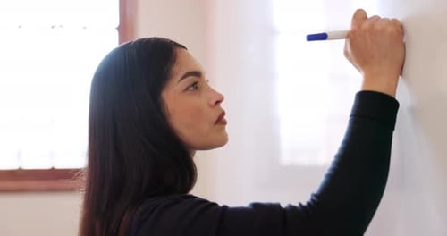 Young Woman Writing on Whiteboard with Blue Marker