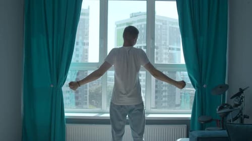 Man Stretching in Apartment Overlooking City