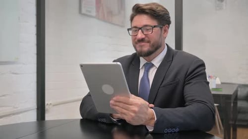 Man in Suit Holding Tablet During Online Meeting