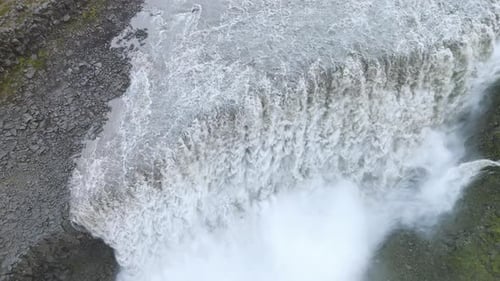 Aerial drone view of crashing glacial water hitting the canyon floor at Dettifoss. Thick spray and m