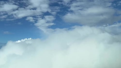 Aerial view from a jet cockpit while flying over the top of clouds