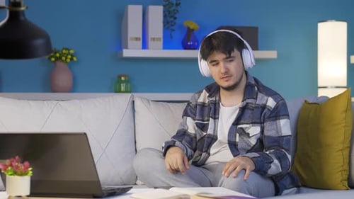 Sad and unhappy man listening to music at night at home.