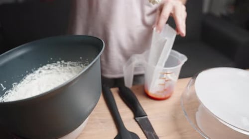 The woman is filling a pastry bag with cream for the cake.