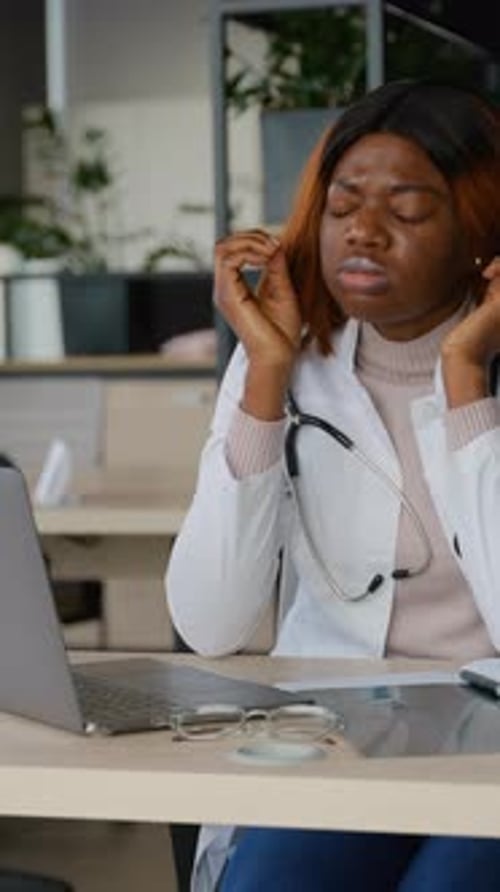 Woman Doctor Massaging Temples at Desk