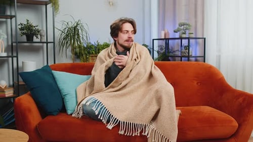 Man Wrapped in Blanket Holding Mug on Couch