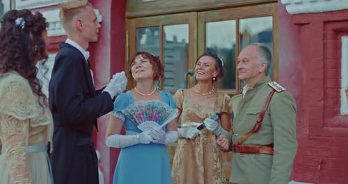 People in Period Clothing Talk Outside Building