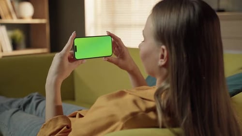 Woman Relaxes on Couch with Chroma Key Phone
