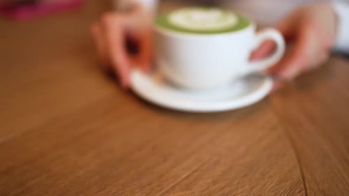 Matcha Latte Close Up with Woman Holding Cup