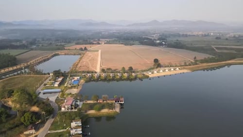 Aerial Orbital Drone Shot of a Lake and Hotel Resort with Scenic Landscape in the Background in Thai