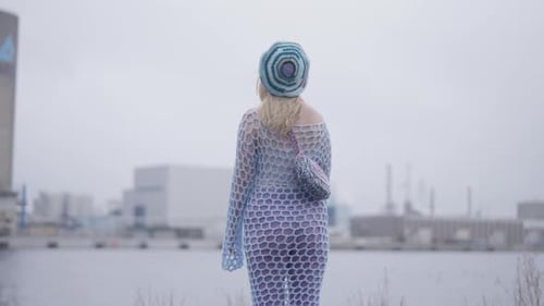 Blonde Woman in Knitted Dress Stands by Water