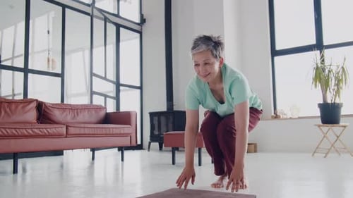 Woman Unrolls Yoga Mat and Stretches in Bright Room